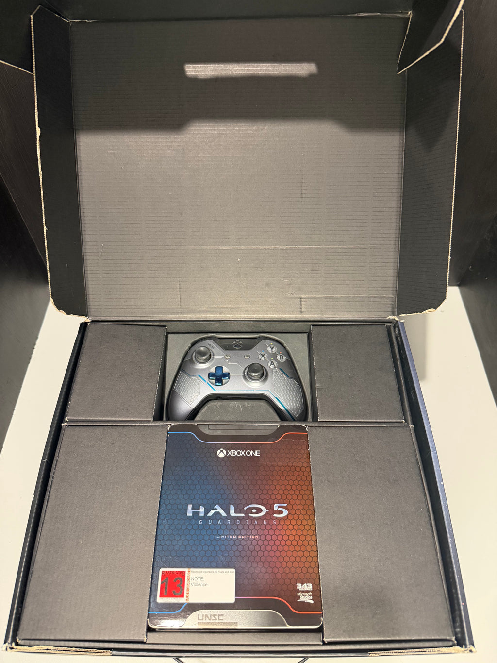 Xbox One 1TB Halo 5 Guardians Limited Edition console front showing UNSC Halo 5 themed finish alongside original outer box