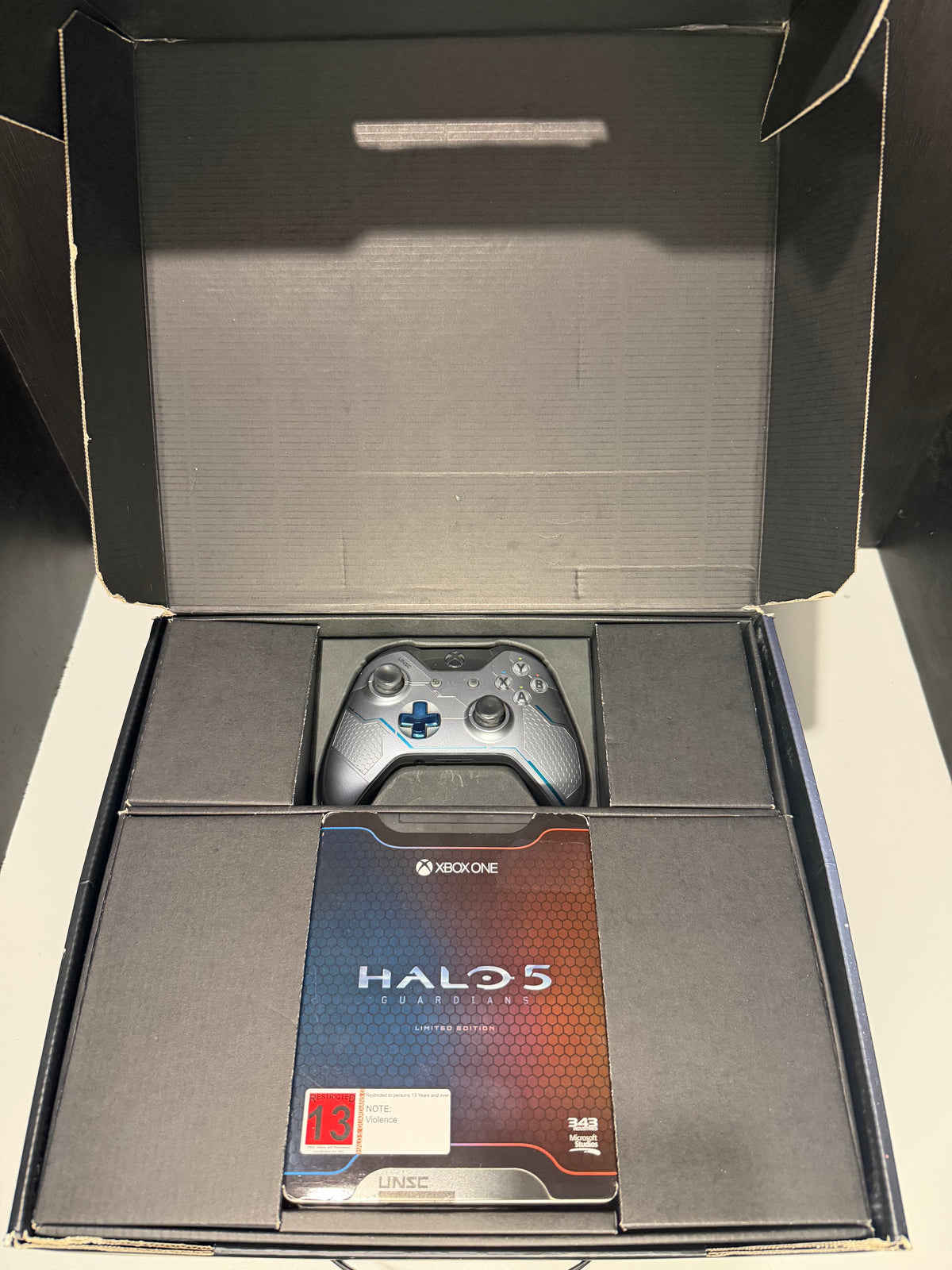 Xbox One 1TB Halo 5 Guardians Limited Edition console front showing UNSC Halo 5 themed finish alongside original outer box