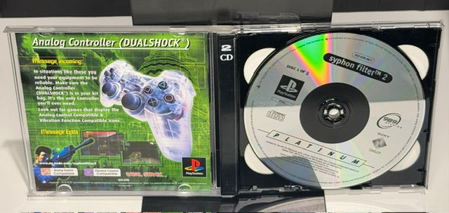 Syphon Filter 2 PS1 Platinum open case showing both Platinum discs Disc 1 and Disc 2 and original manual with DualShock controller advertisement