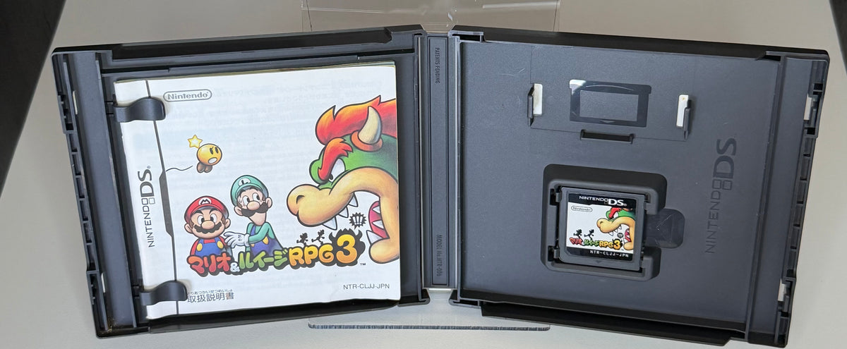 Mario and Luigi Bowsers Inside Story Nintendo DS Japanese open case showing manual on left side and cartridge seated in right tray