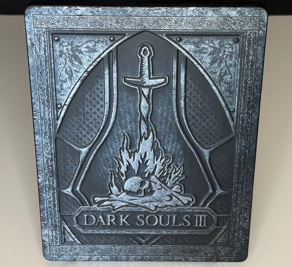 Dark Souls III SteelBook Edition PS4 front showing embossed bonfire and sword motif with Dark Souls III title relief on metal case