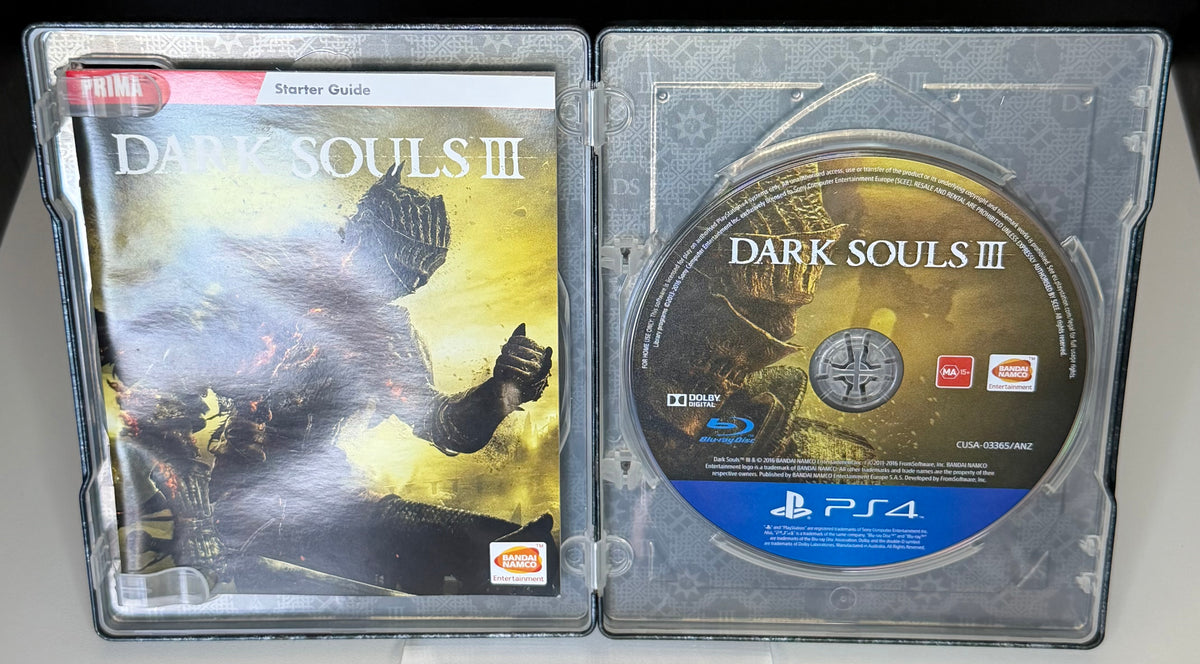 Dark Souls III SteelBook Edition PS4 open case showing Prima Starter Guide on left and Dark Souls III Blu-ray disc ANZ pressing on right