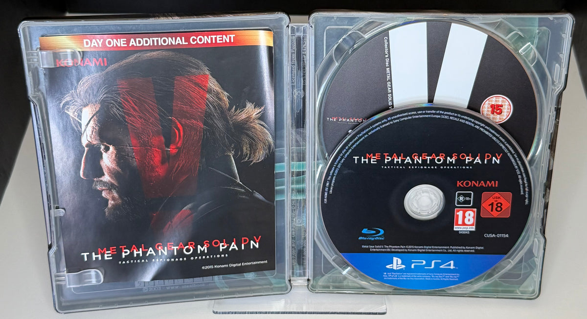 Metal Gear Solid V Phantom Pain Day One SteelBook PS4 open case showing Day One Additional Content inlay on left and CUSA-01154 European Blu-ray disc on right
