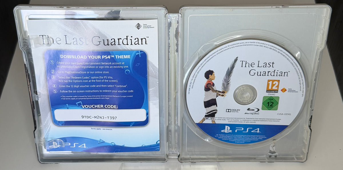 The Last Guardian SteelBook Edition PS4 open case showing PS4 Theme voucher card with visible voucher code on left and CUSA-03745 European Blu-ray disc on right