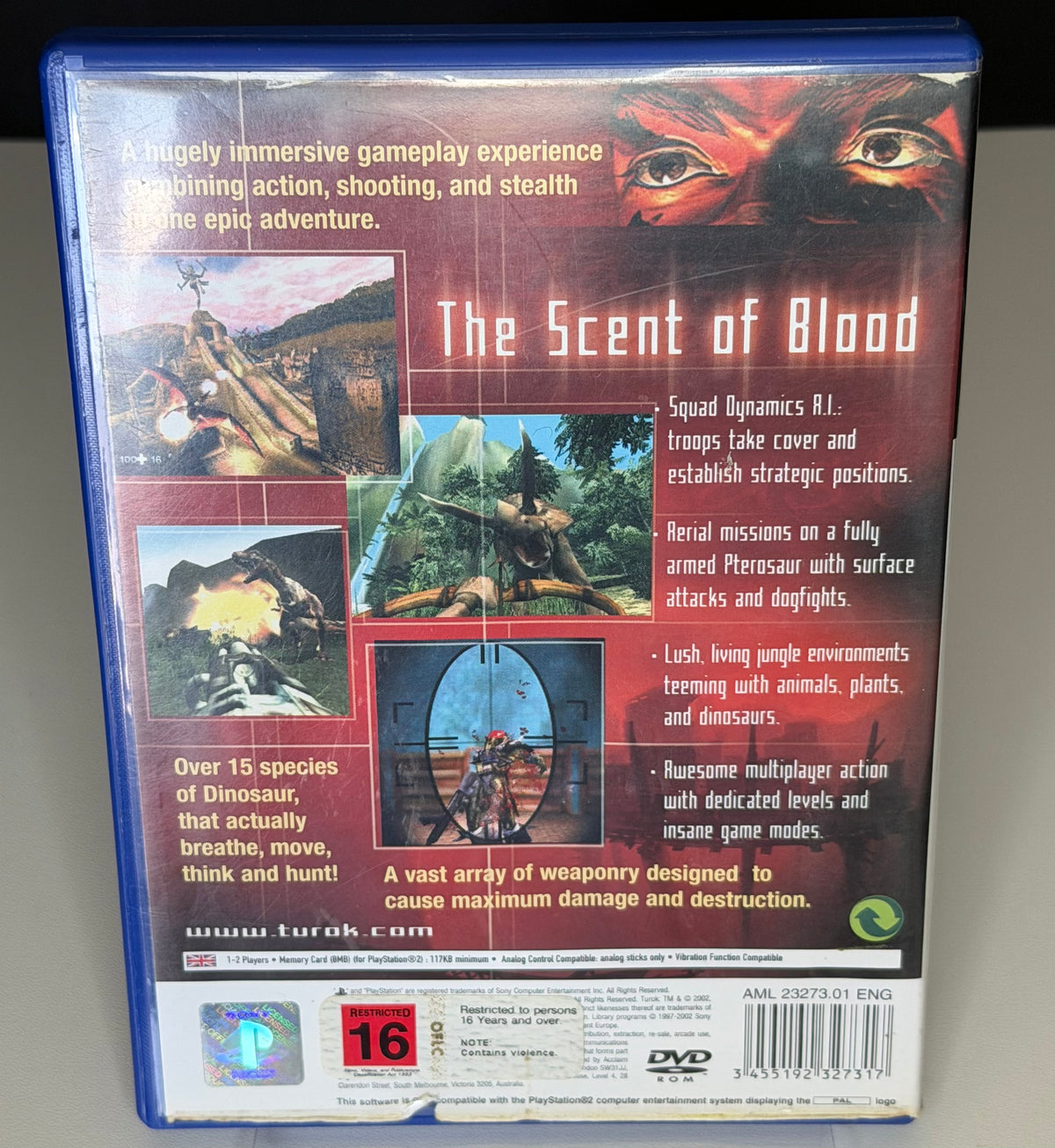 Turok Evolution PS2 back cover showing gameplay screenshots and The Scent of Blood tagline with Restricted 16 rating and AML 23273.01 ENG barcode on blue PS2 case